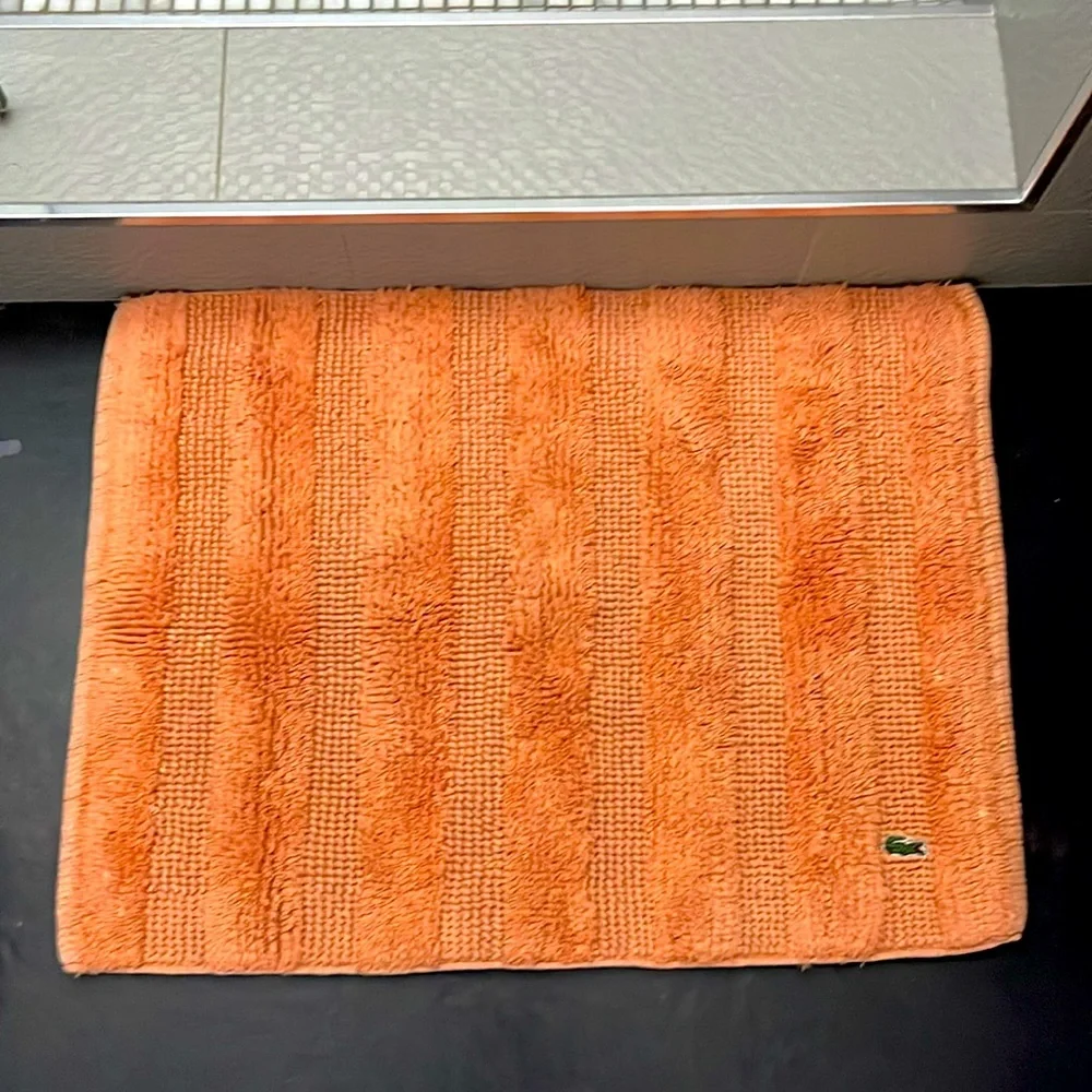 Set of two Lacoste bathroom mats in orange.